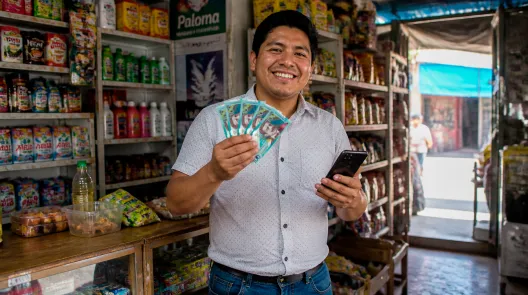 Hombre peruano sonriente con billetes de soles y celular tras recibir su préstamo de 500 soles al instante en el Perú